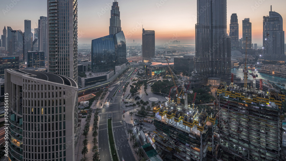 Fototapeta premium Panoramic skyline view of Dubai downtown before sunrise with mall, fountains and skyscrapers aerial night to day timelapse