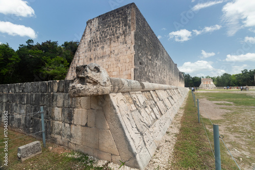 head of a snake in the corner of ancient mayan ball game field with warriors caerved stone into Chichen Itza archaeological site