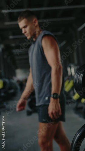 Young man in gym, showcasing determination and focus. Ready for workout in modern fitness center. Represents fitness, health, and dedication. Focused Man in Gym Setting Preparing For Workout Vertical