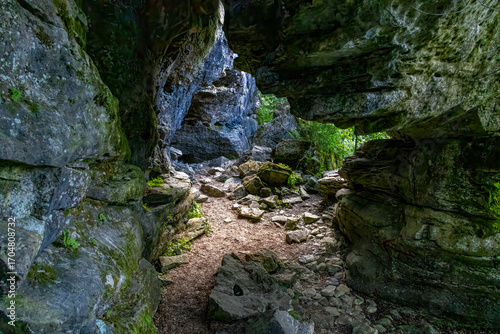 The entrance to Grieg's Caves in Ontario invites exploration amid the stunning natural rock formations and lush greenery.