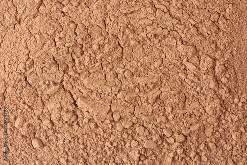 reddish-brown rock phosphate powder with cracked surface and granular texture, essential nutrient for plants, used as agricultural fertilizer, close-up taken from above