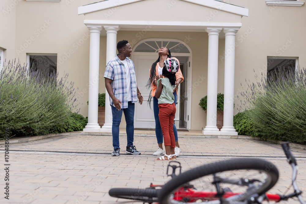 Fototapeta premium Outside home, African American family spending time together with bicycle in foreground