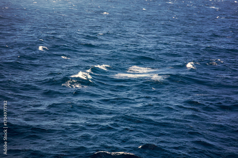 Fototapeta premium Blue sea water surface with waves and foam. Natural background.