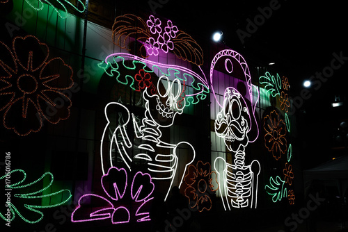 A large sign with skeletons and flowers on it. The skeletons are wearing hats and the flowers are in the background. Mexico, zacatlan de las manzanas, puebla, day of the dead mexican tradition