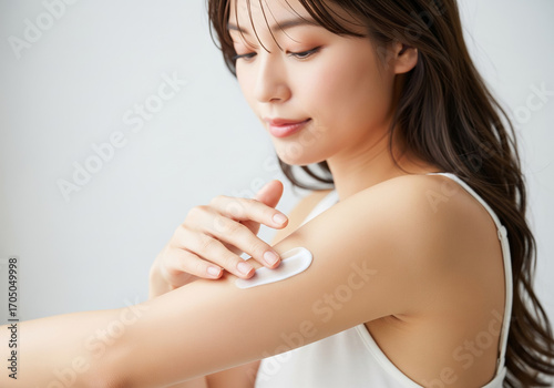 腕にクリームを塗る、艶やかな肌の女性