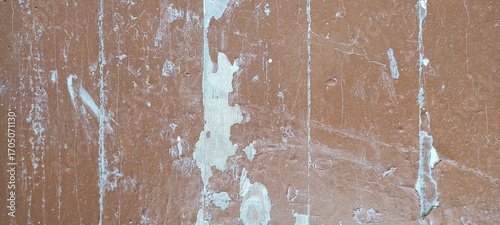 Worn-out wooden surface with peeling brown paint revealing lighter undercoat, displaying vertical streaks and natural textures, suggesting weathering and aging over time