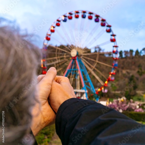 Hands clasped in front of a Ferris wheel