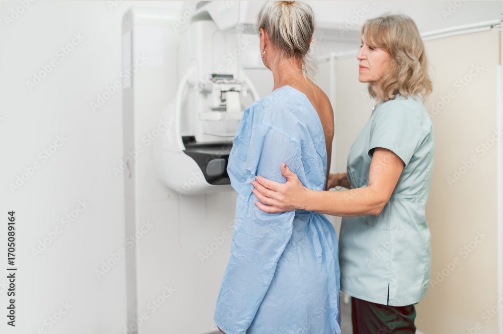 Fototapeta premium woman patient undergoes mammography procedure on mammograph digital mammography machine in modern clinic with doctor. Regular medical examination, screening for breast cancer 