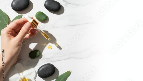 Hand Holding Cosmetic Dropper Over Spa Stones in Upscale Flatlay Arrangement with Natural Elements for Relaxation and Wellness Aesthetic