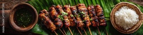 Delicious moo ping pork skewers served on banana leaf with rice and dipping sauce
