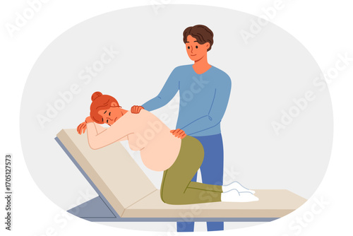 Man gives massage to pregnant woman kneeling on hospital bed waiting for labor to begin. Caring husband takes care of pregnant wife experiencing back pain while awaiting birth of child.