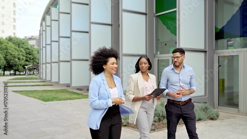 Video of Three multiracial business colleagues discussing project on their way to office in city