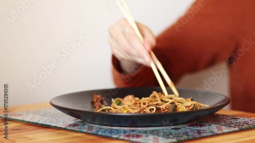 Learning to Use Chopsticks. A Difficult but Fun Challenge. chinese food concept. A Delicious Chinese Meal. Eating Spicy Noodles with Chopsticks