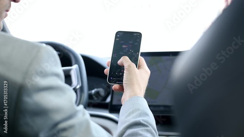 A man is driving a car and looking at his cell phone