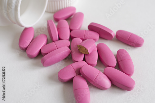 pink pills and bottle on a white background close-up.