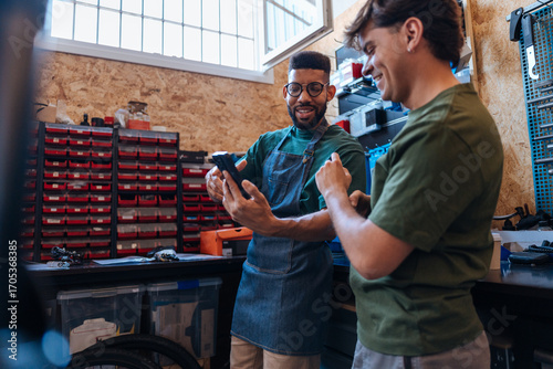 Bicycle mechanics using mobile phone in workshop