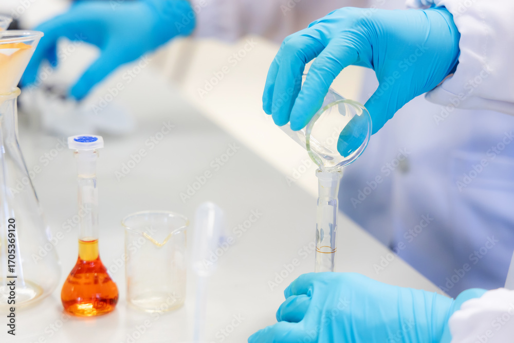 Fototapeta premium A scientist performs a borax detection test in a laboratory using an orange chemical solution inside a volumetric flask. Represents chemical analysis, food safety research in laboratory.