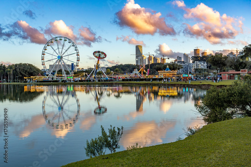 Vibrant Barigui Park in Curitiba, capital and largest city in the state of Parana, featuring a funfair and a ferris wheel against the city skyline. Brazil.