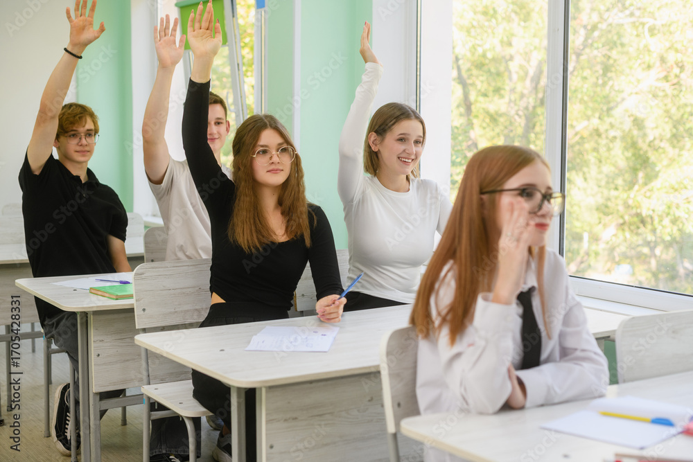 Fototapeta premium High school students raising hands to answer question in class.