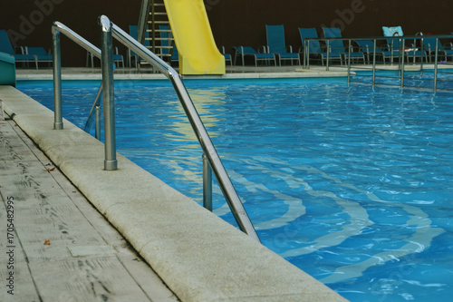 Fragment of a swimming pool with blue water and railings, handrails, fences.