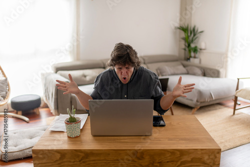 Angry Man Gesturing in Front of Laptop at Home