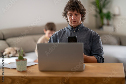 Man Working Focused at Home with Laptop and Plant
