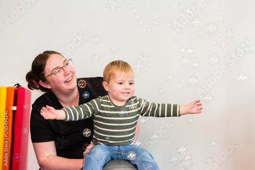 Child sitting on therapy ball playing with bubbles strengthening movement exercise