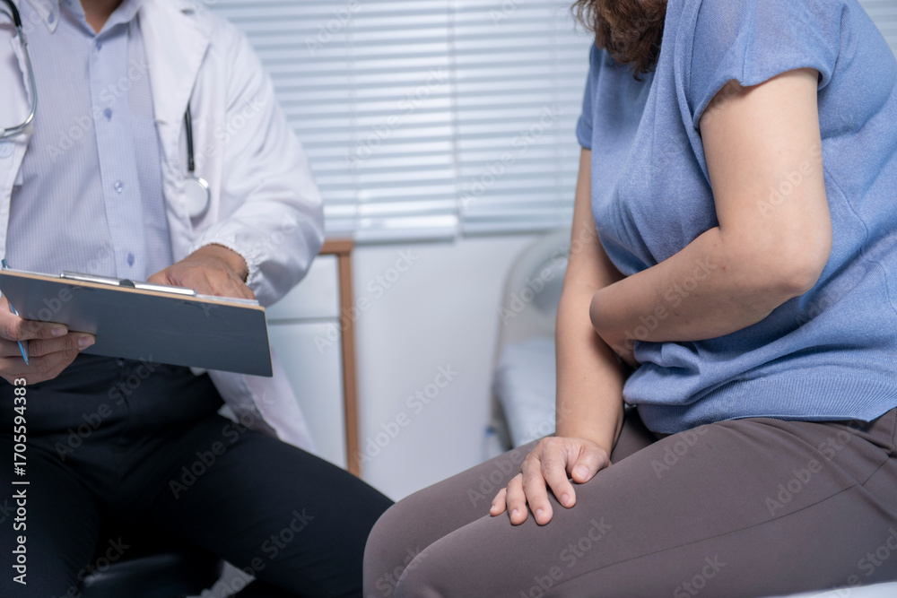 Obraz premium Doctor taking notes while patient suffering abdominal pain in hospital