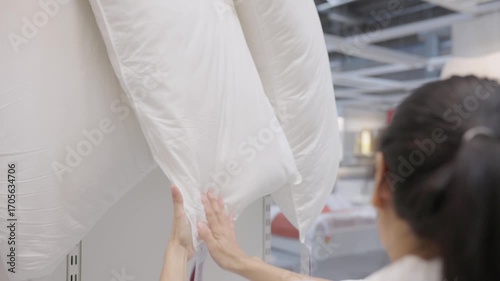 Focused shopper examining plush pillows in retail store display, highlighting comfort, quality, texture, lifestyle choice, and bedroom home decor accessory shopping decision experience