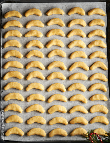 Raw sweet pastry on a baking sheet - preparation of vanilla crescents or Kipferl, traditional Christmas cookies