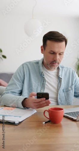 Vertical video of adult man at home paying with mobile phone for online shopping 