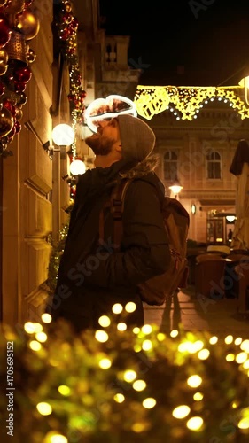 Wallpaper Mural Vertical 4k footage of a young man with a backpack admiring festive Christmas decorations on a city street illuminated with holiday lights at night Torontodigital.ca