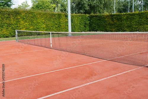 Wallpaper Mural Tennis court with a net on a clay surface, surrounded by lush greenery for an inviting atmosphere Torontodigital.ca