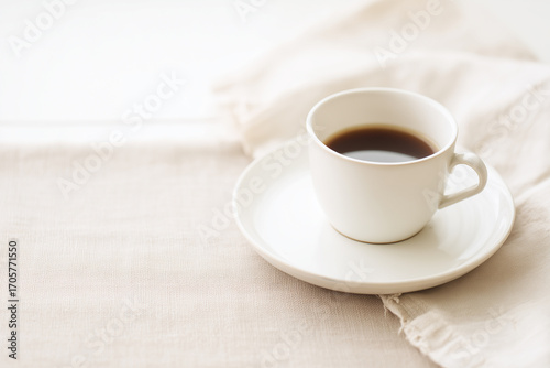 Cup of black coffee on light fabric background