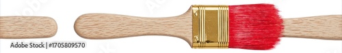 A paintbrush dipped in red paint is lying horizontally on a white surface, its wooden handle slightly disconnected