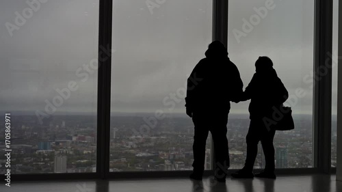 Silhouetted and anonymous tourists enjoying panoramic view of London from high rise observatory