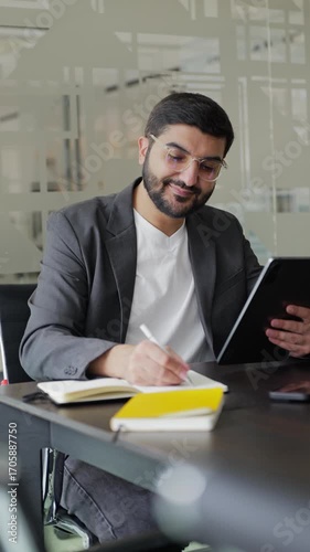 Man in office is working with a tablet near notebook