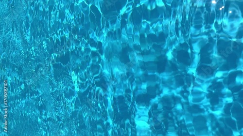 Close up of bright blue swimming pool water during daytime with rippling water creating interesting patterns