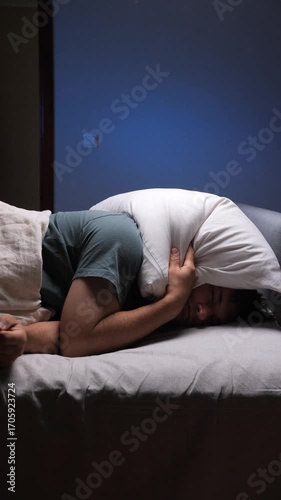 vertical video Man covering his head with pillow trying to sleep