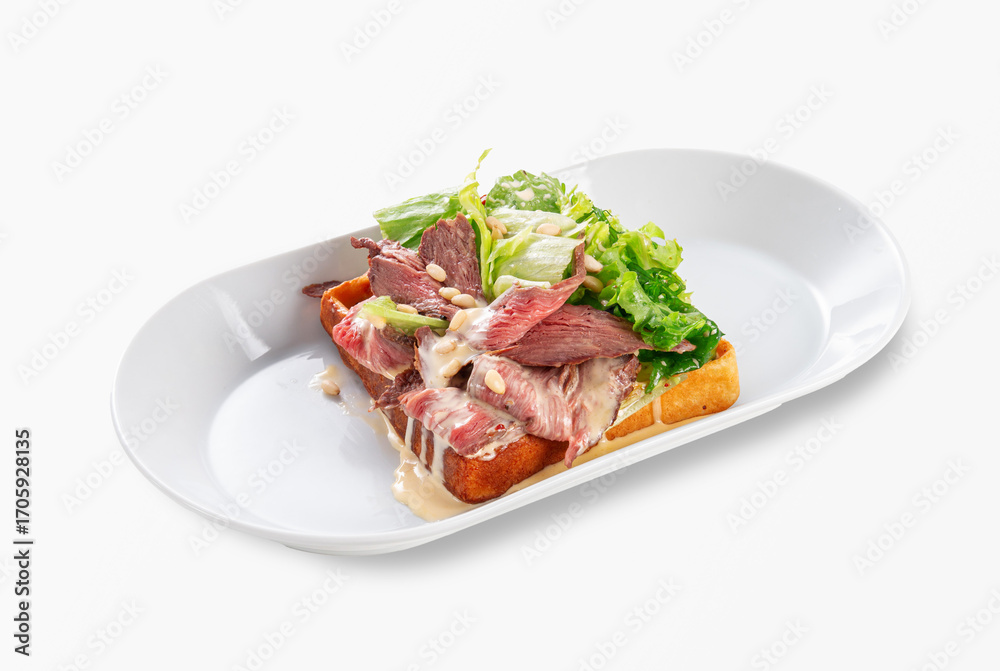 Gourmet toast with slices of roast beef, fresh lettuce, pine nuts and creamy sauce served on white plate, isolated on white background, restaurant style Gourmet toast with slices of roast beef, fresh lettuce, pine nuts and creamy sauce served on white plate, isolated on white background, restaurant style