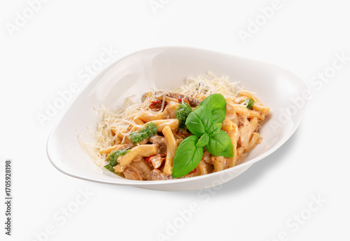 Traditional Italian casarecce pasta served with creamy mushroom sauce, grated parmesan cheese, pesto and fresh basil leaves in a white plate, classic homemade comfort food, isolated on white