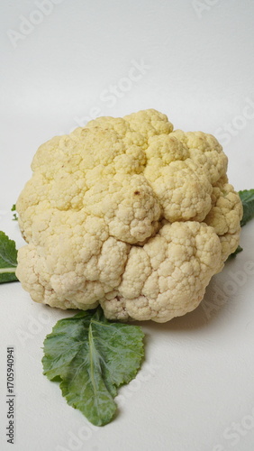 Isolated white cauliflower is whole, raw and green leafy cauliflower.