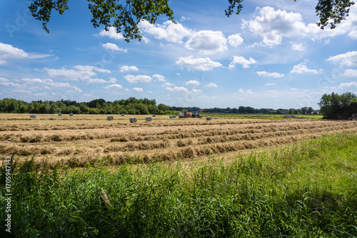 A tractor in a field in the countryside baling hay