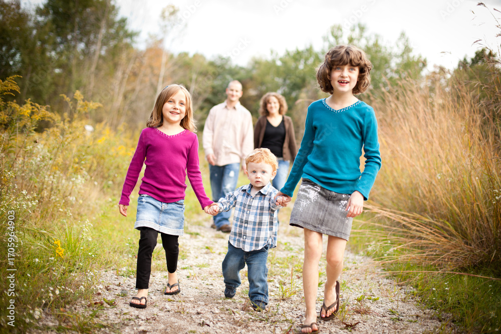 Fototapeta premium Happy Sisters and Brother Walking with Dad and Mom in Nature