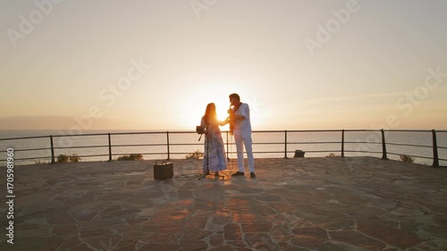 Singers and guitarist perform together on a scenic oceanfront terrace at dusk