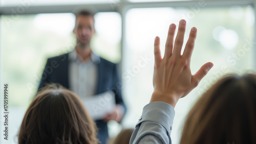 Engaged audience member raising hand during presentation, seeking clarification or asking question in professional setting