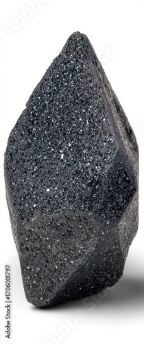 Dark, metallic crystalline mineral with rough, multifaceted texture, resting on a white surface. Shadowing suggests a light source from above