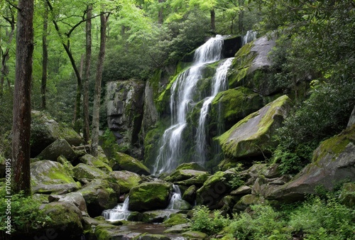 Scenic cascade tumbles down mossy rocks in a dense green forest, creating a peaceful nature scene. Sunlight filters through the canopy above