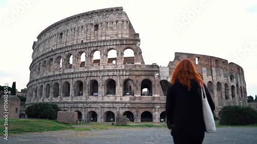 Woman walking towards Colosseum through archway gate