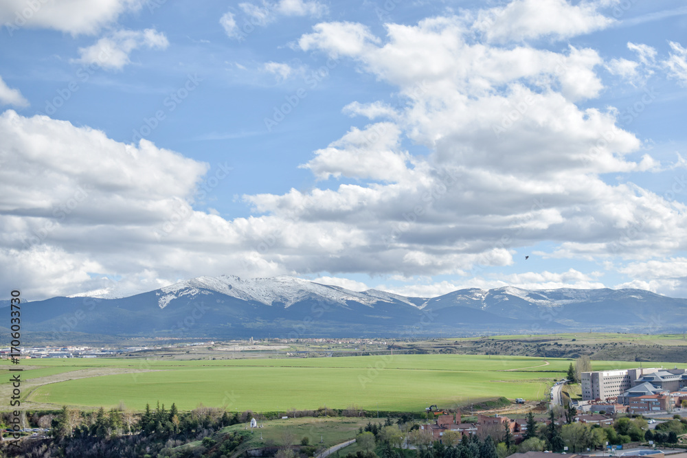 Fototapeta premium Snowy mountain from the rooftops of a village with sunny day and clear clouds